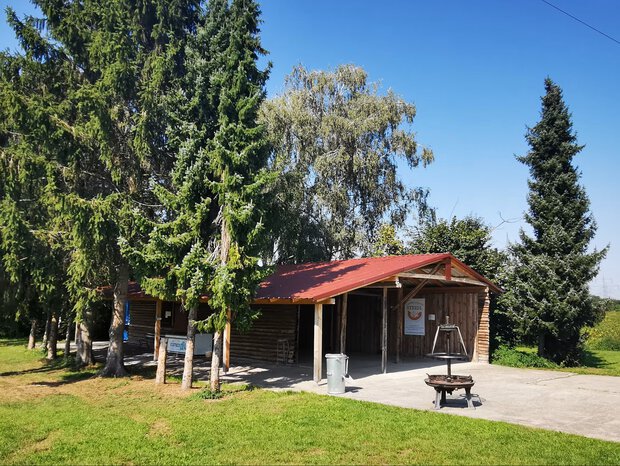 Ein Foto von Steidl´s Grillhütte worauf die Hütte, der Grill und schattenspendende Bäume zu sehen sind.
