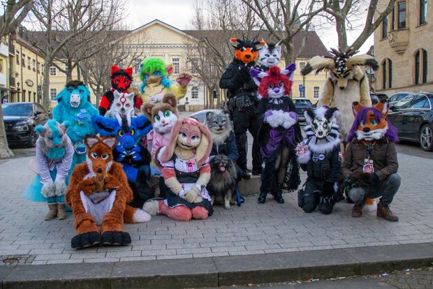 Gruppenfoto mehrerer Fursuiter vor einem Brunnen mit einer riesigen Steinkugel vor der Spielbank in Bad Dürkheim.