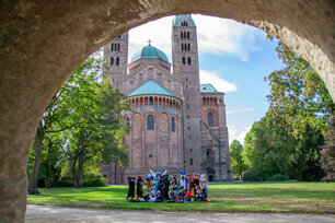 Eine Gruppe Fursuiter auf der Wiese im Domgarten vor der Rückseite des Speyerer Doms.